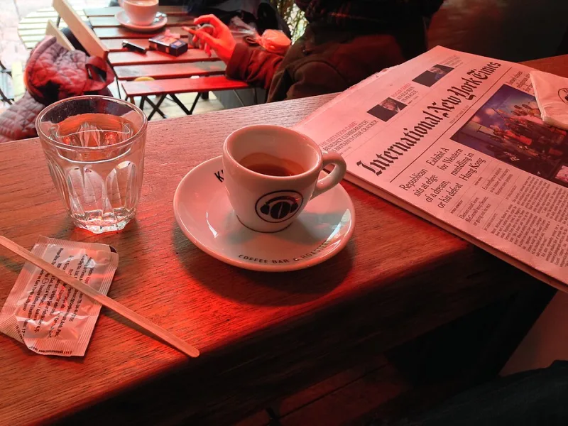 Taza de cafe junto a un periodico sobre una mesa