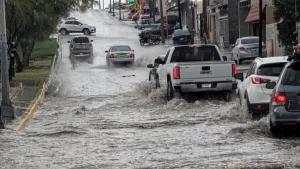 Vehiculos circulan por una calle inundada tras lluvia intensa