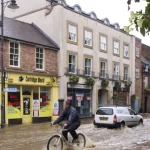 Persona en bicicleta avanza por una calle inundada