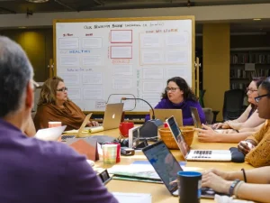 Equipo editorial reunido alrededor de una mesa de trabajo con laptops y notas