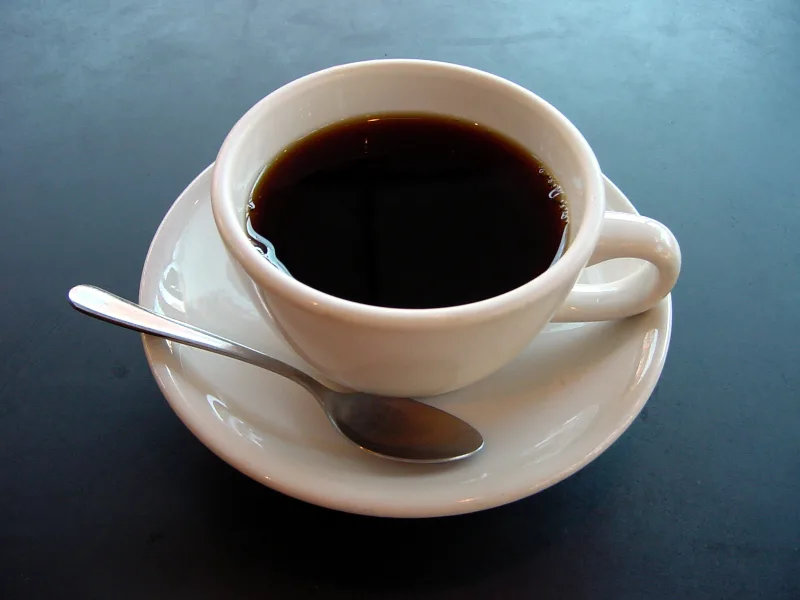 Taza pequeña de café negro sobre una mesa