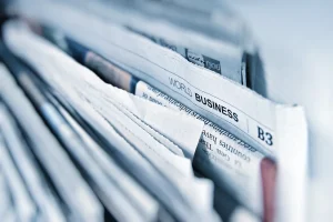 Periódicos y libreta sobre una mesa de trabajo editorial
