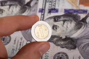Moneda mexicana sobre billetes de dólar estadounidense