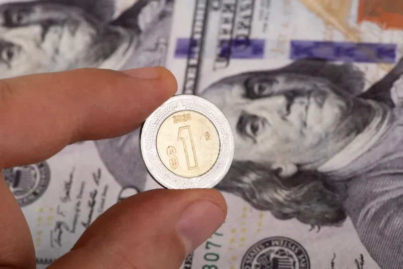 Moneda mexicana sobre billetes de dólar estadounidense
