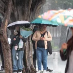 Personas bajo la lluvia, imagen ilustrativa de archivo